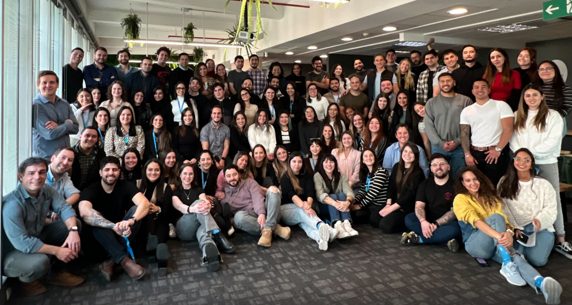 Foto de grupo del equipo de Rindegastos, mostrando a más de cincuenta colaboradores sonrientes en una oficina, reflejando un ambiente de trabajo colaborativo y diverso