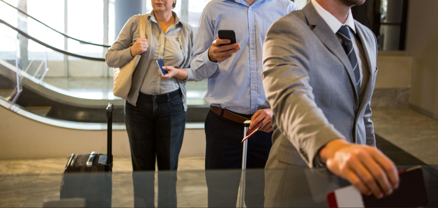 Viajeros corporativos en fila para control de pasaportes, listos para gestionar viáticos de manera eficiente.