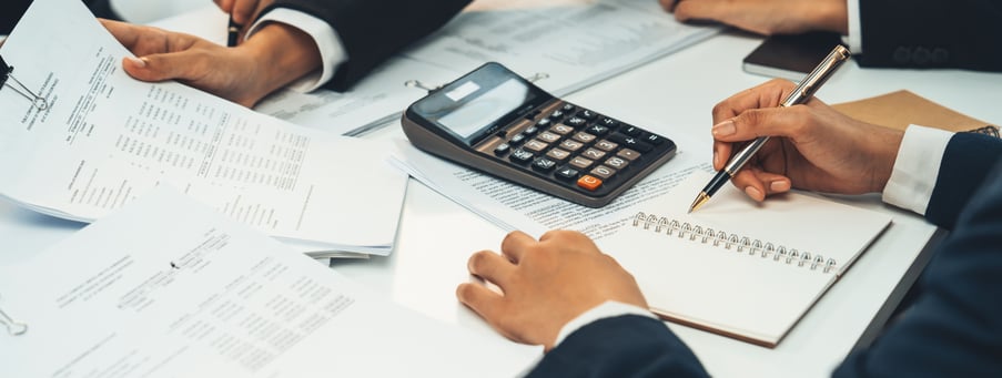 Equipo de contadores trabajando en informes financieros con una calculadora y documentos en la mesa.