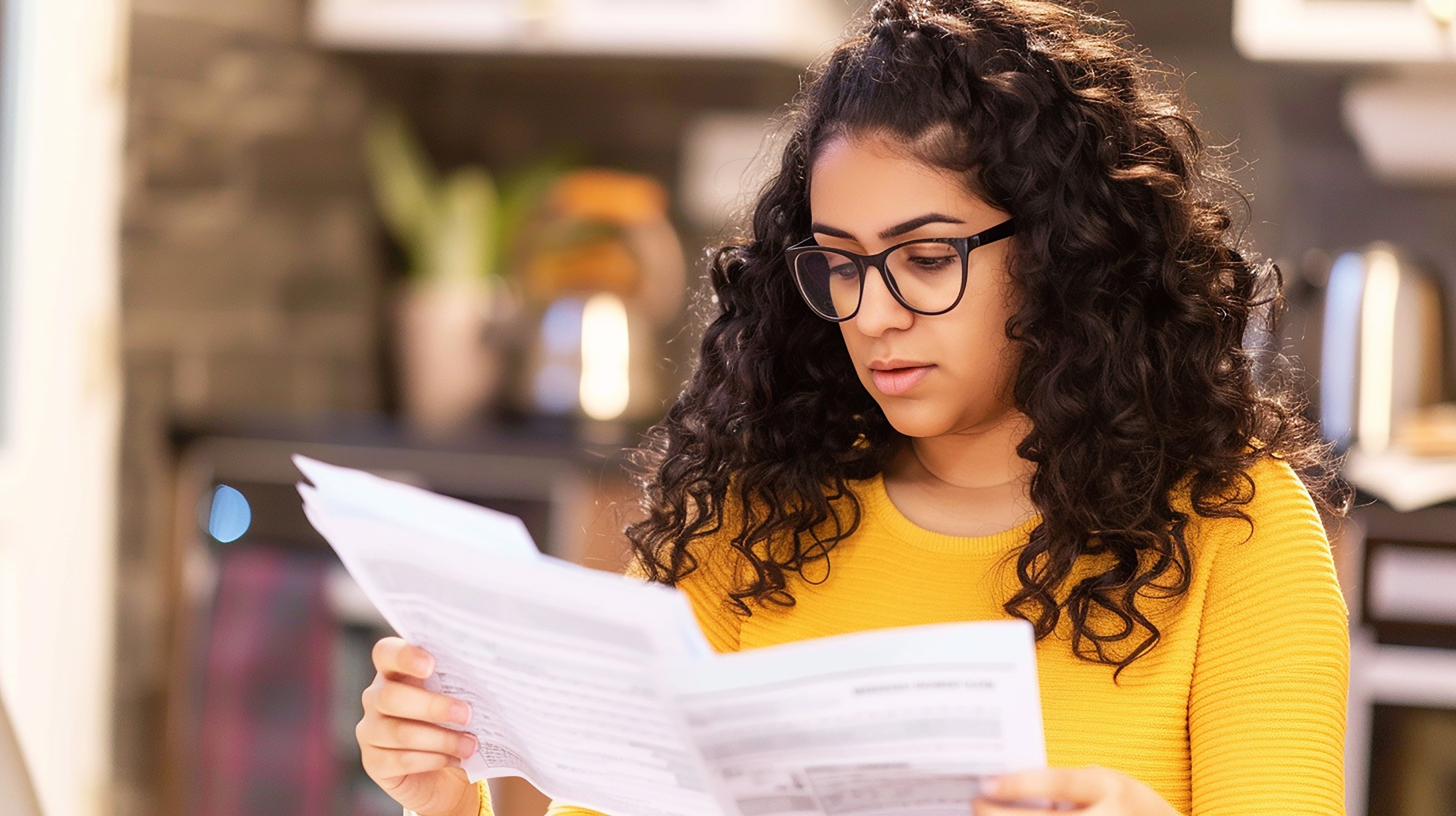 Mujer con gafas revisando cuidadosamente un facturas que parecen ser iguales